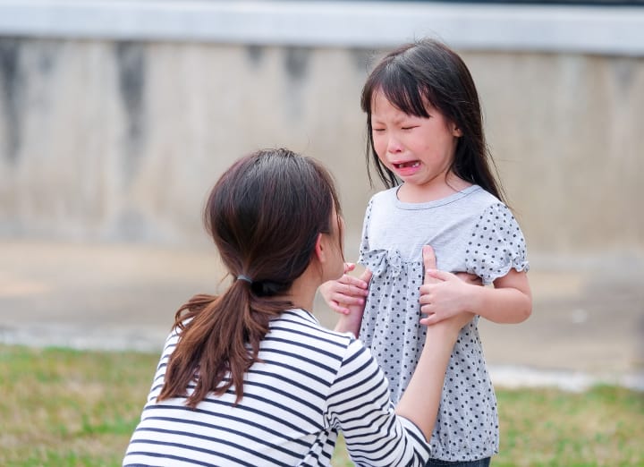 Mother dealing with three year old tantrums to try to stop toddler from having a temper tantrum from screaming when angry