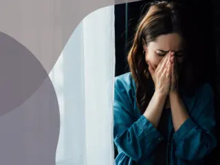 woman crying in the dark next to the window curtain