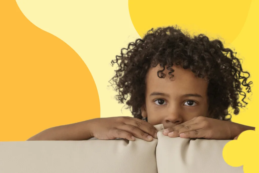 child scared hiding behind couch