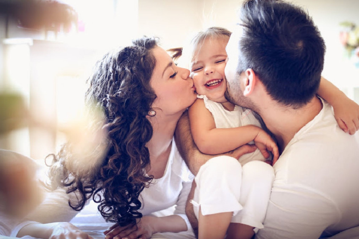 Mother and father kiss baby affectionately in good parenting skills articles