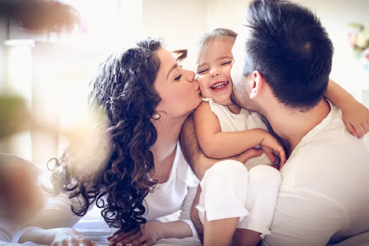 La mère et le père embrassent affectueusement bébé dans des articles sur les bonnes compétences parentales