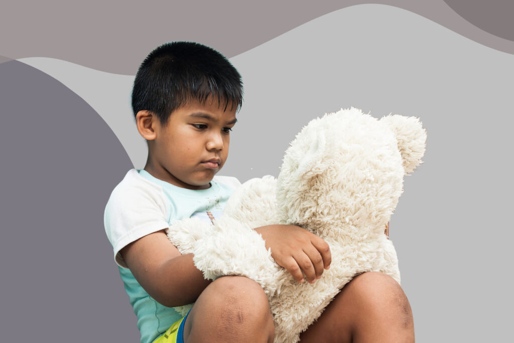 boy holding teddy bear sad