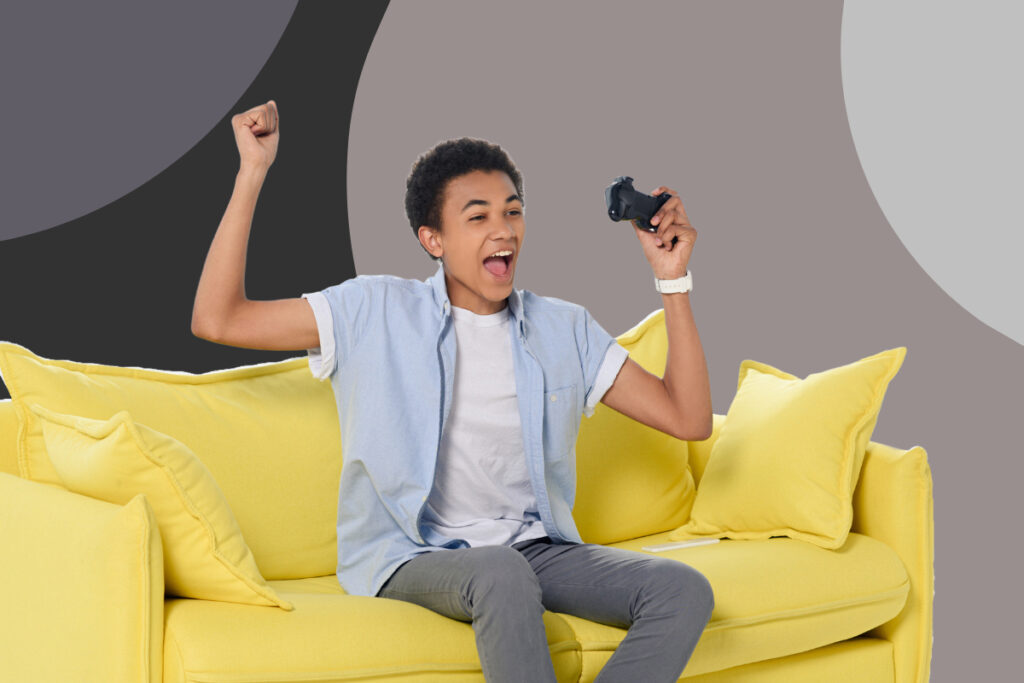 A teenage boy holding a gaming controller and celebrating.
