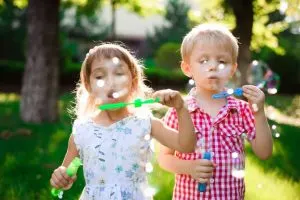 a boy and a girl blow bubbles in the park - importance of play
