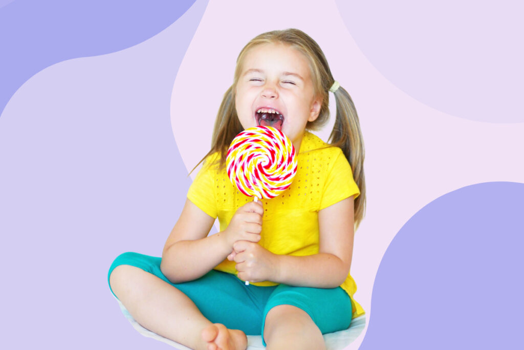 An excited girl holding a big lollipop.
