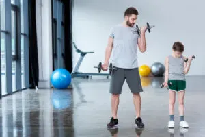 father son lift weights together in gym