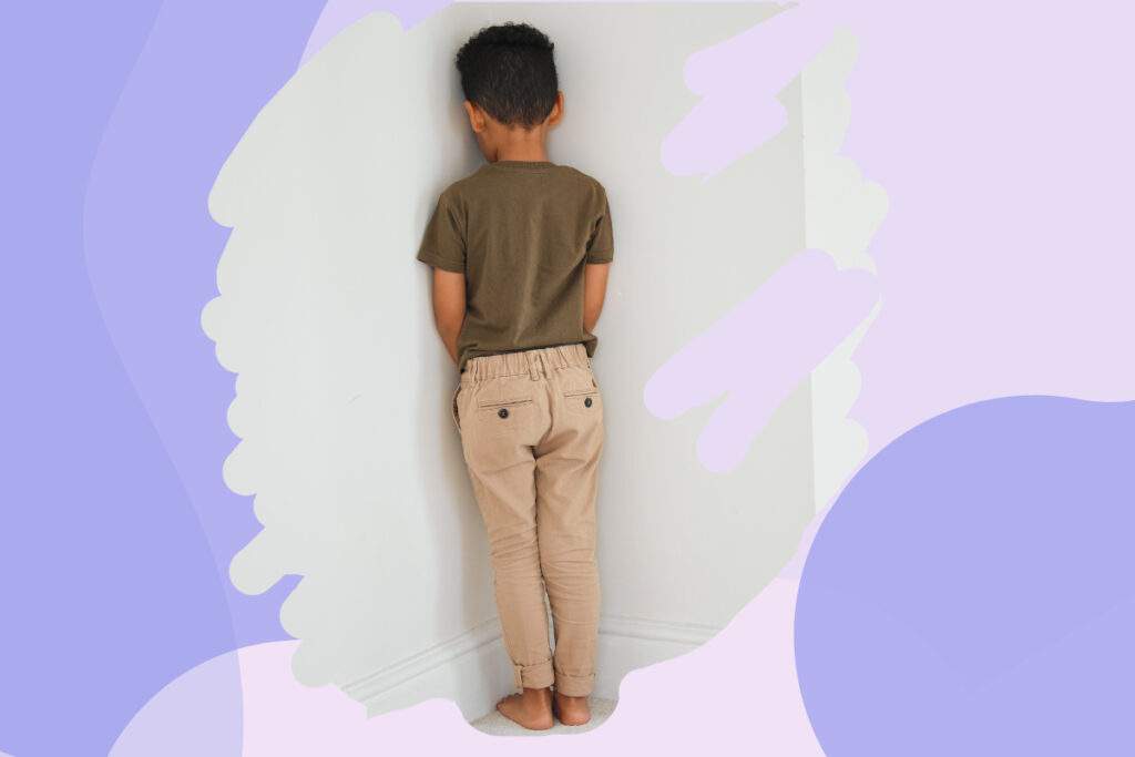 A boy standing and facing the wall in time-out.