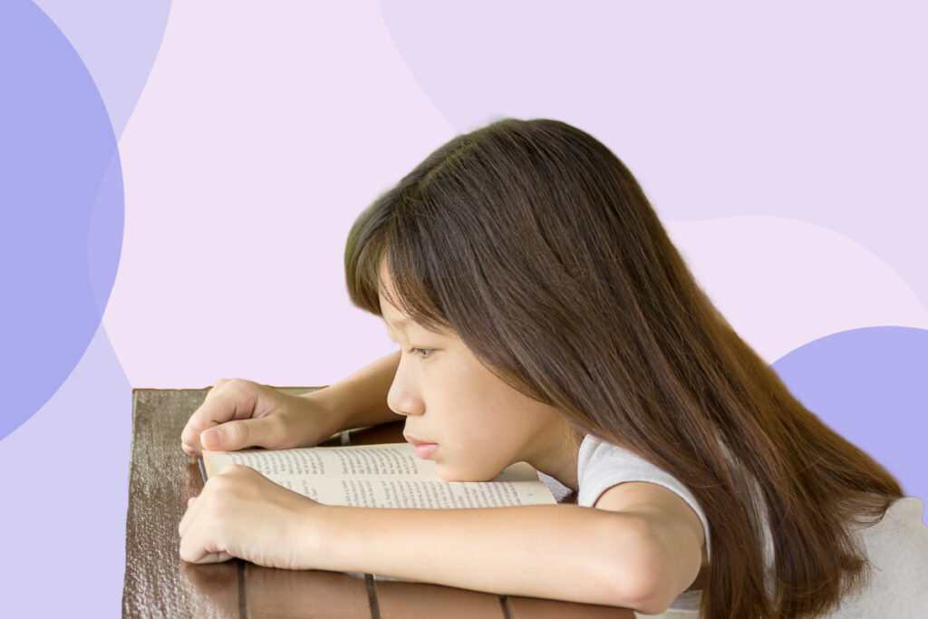 A young girl lying down on her book.