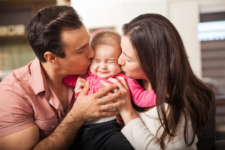 Mother and father kiss baby affectionately - good parenting skills