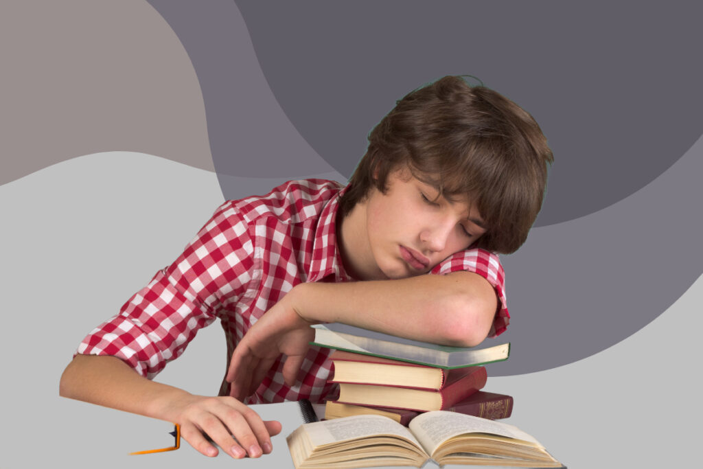 teenage boy falling asleep on a pile of books