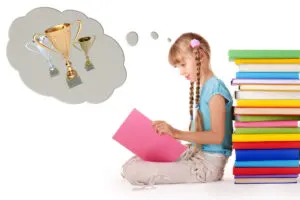 girl sits against a pile of books, reads book, dreams about trophy