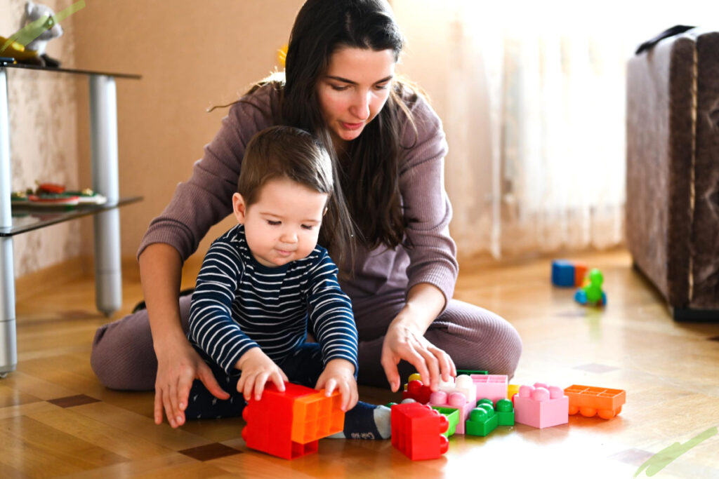 mother plays toys with toddler on the floor to improve the child’s behavior
