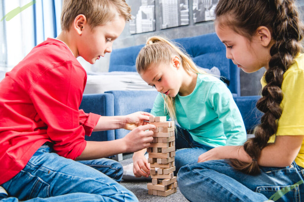 three kids play jenga together social development examples