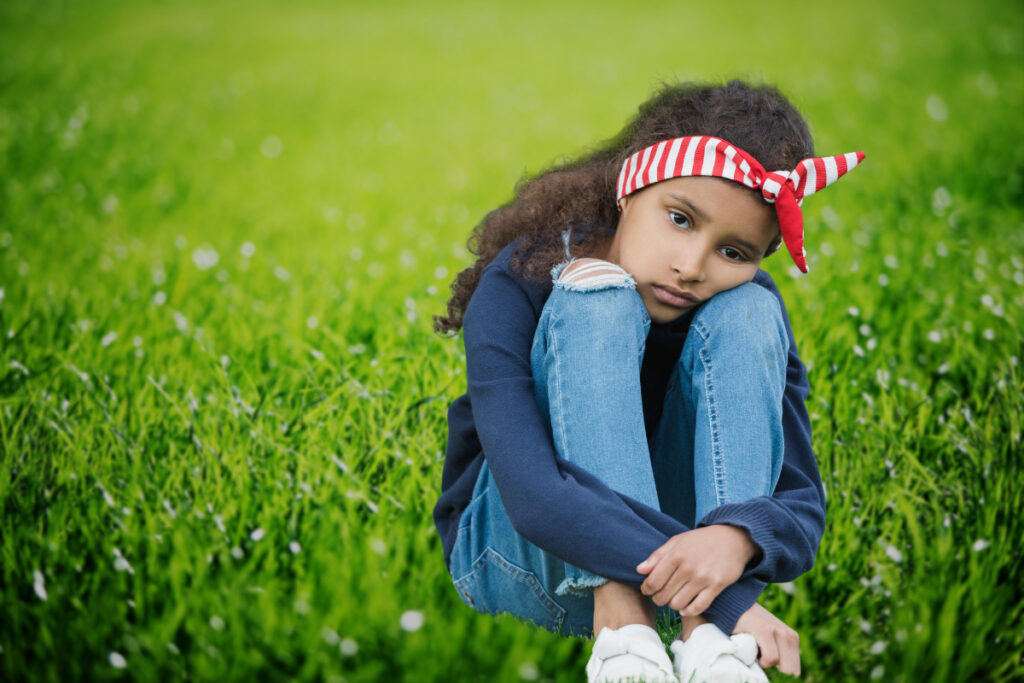 girl sits on grass thinks and looks sad suppressing thoughts