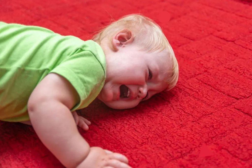 boy cries lying on red carpet