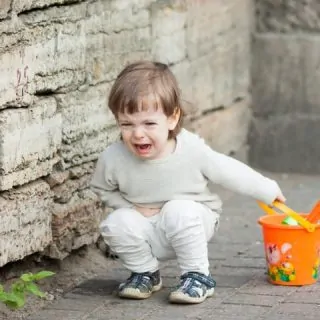 Toddler kneeling on ground having a temper tantrum