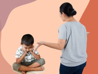 A mother stands yelling at her child, who is sitting with his face in his hands.