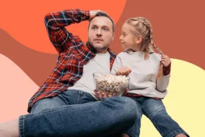 girl watches dad who holds a bowl of popcorn and looks surprised
