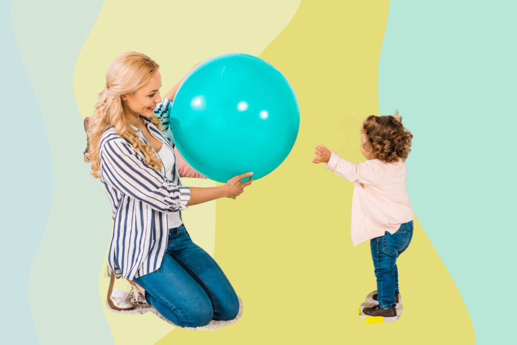 A woman throws a big plastic ball to her small child.