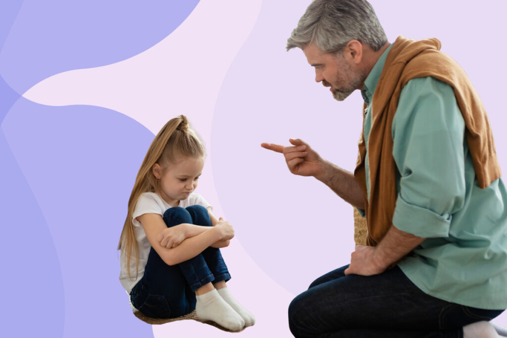 A dad kneeling and scolding his daughter who is sitting on the floor.